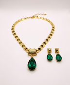 Gold necklace with green gemstones on a white background