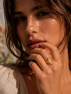 Close-up of a woman with a gold ring on her finger, outdoors.