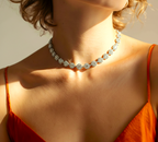 Close-up of a woman wearing a sparkling diamond necklace with an orange top.