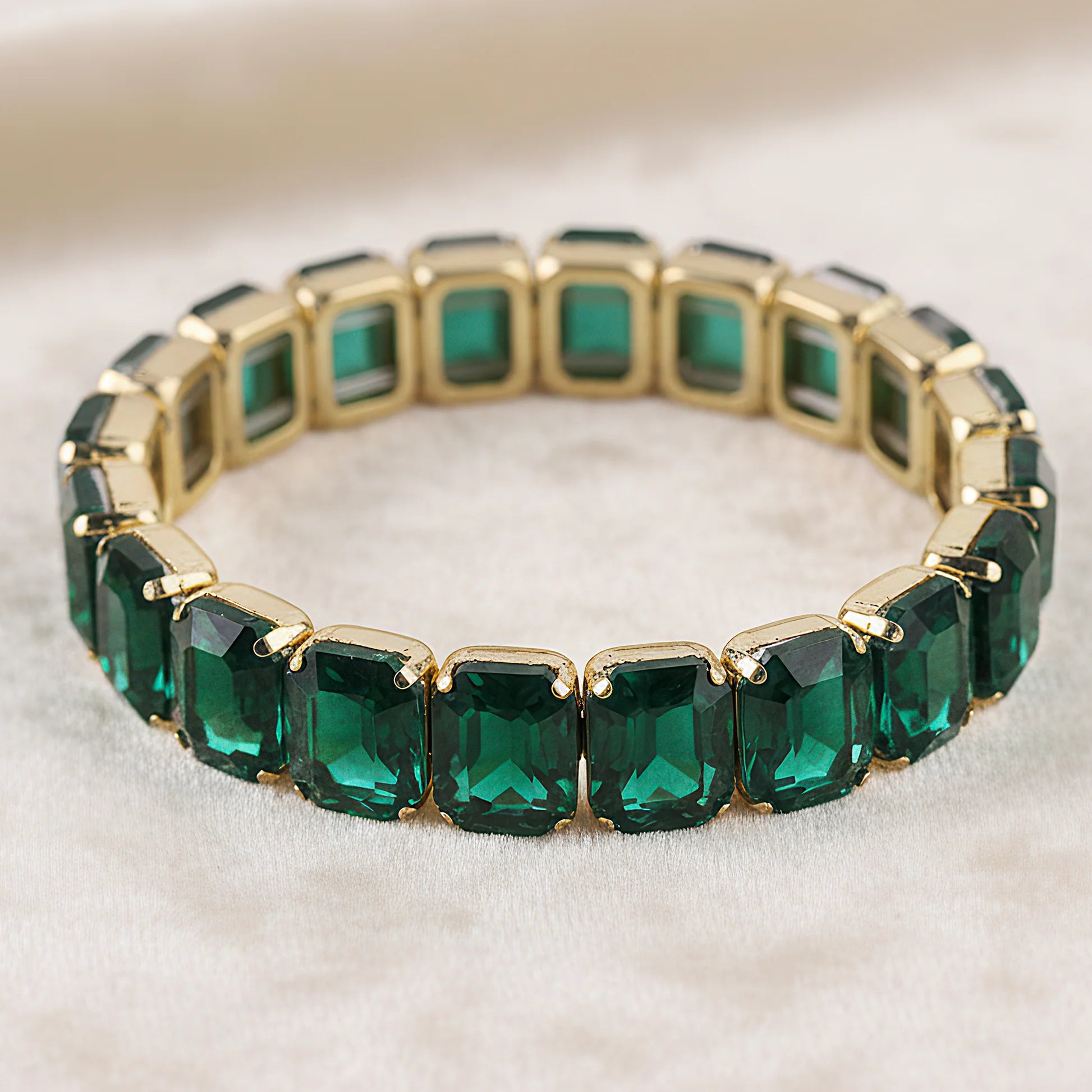 Gold bracelet with emerald on a light background