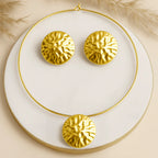 Gold necklace and earrings on a white plate with a beige background
