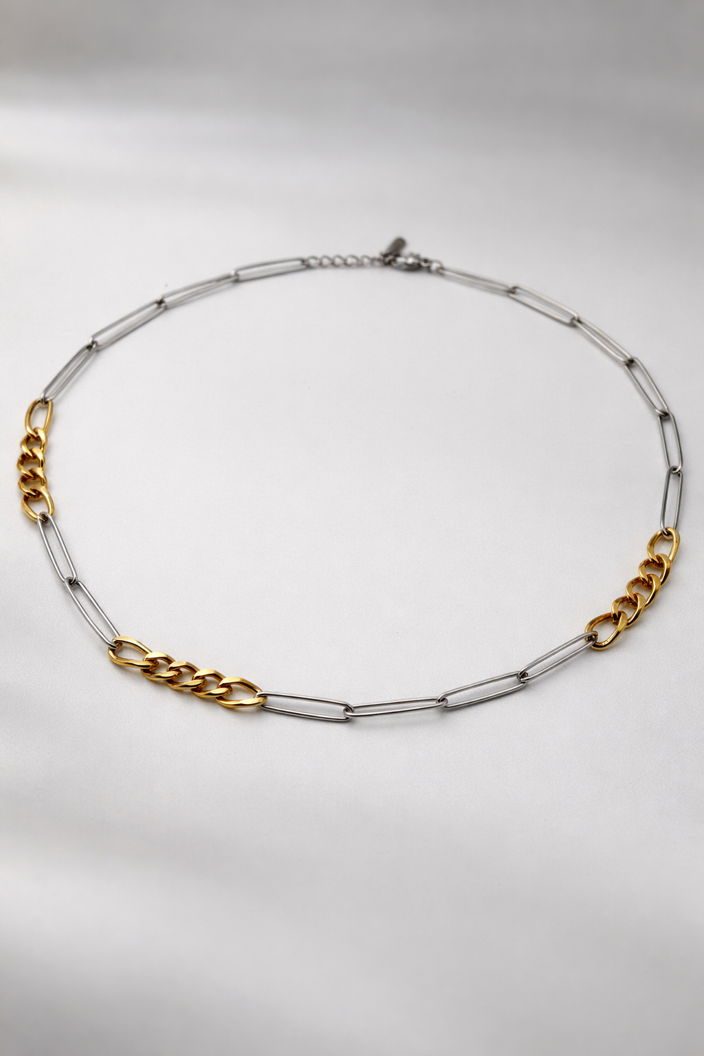 Gold and silver chain paperclip necklace on a light gray background