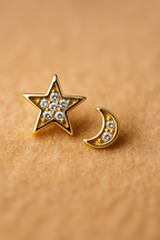 Gold star and moon earrings with CZ accents on a beige background