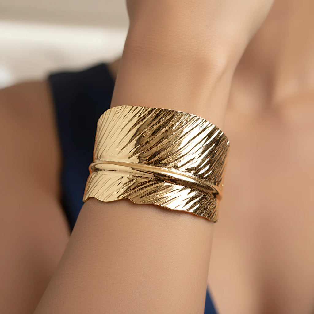Close-up of a person wearing a anti tarnish adjustable  leaf textured golden cuff on their wrist.