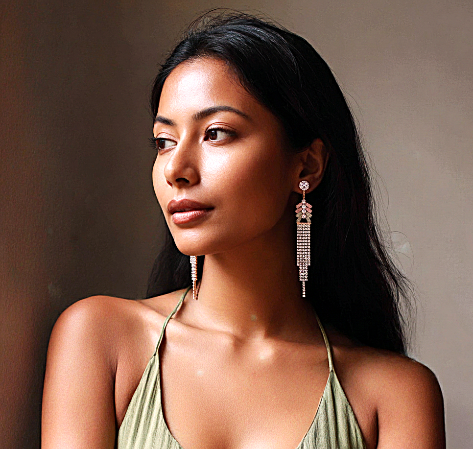 Woman wearing long, dangling earrings against a neutral background