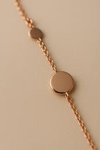 Rose gold necklace with circular polka dots  on a beige background