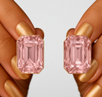 Pink crystal earrings held between fingers with a neutral background