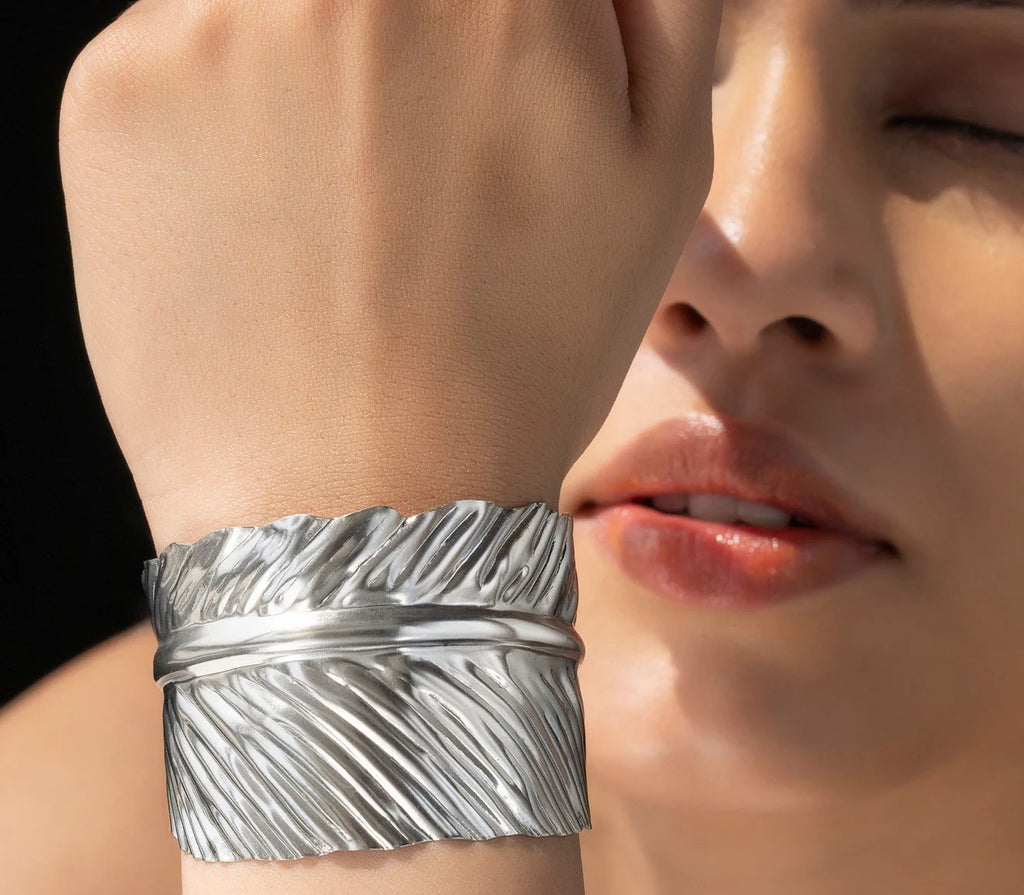 Close-up of a person wearing a anti tarnish adjustable leaf textured silver cuff on their wrist.