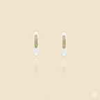 Pair of gold and white earrings on a beige background