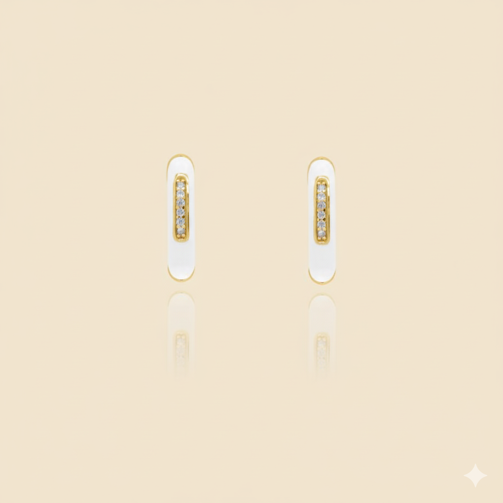 Pair of gold and white earrings on a beige background