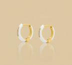 Gold and white hoop earrings on a beige background