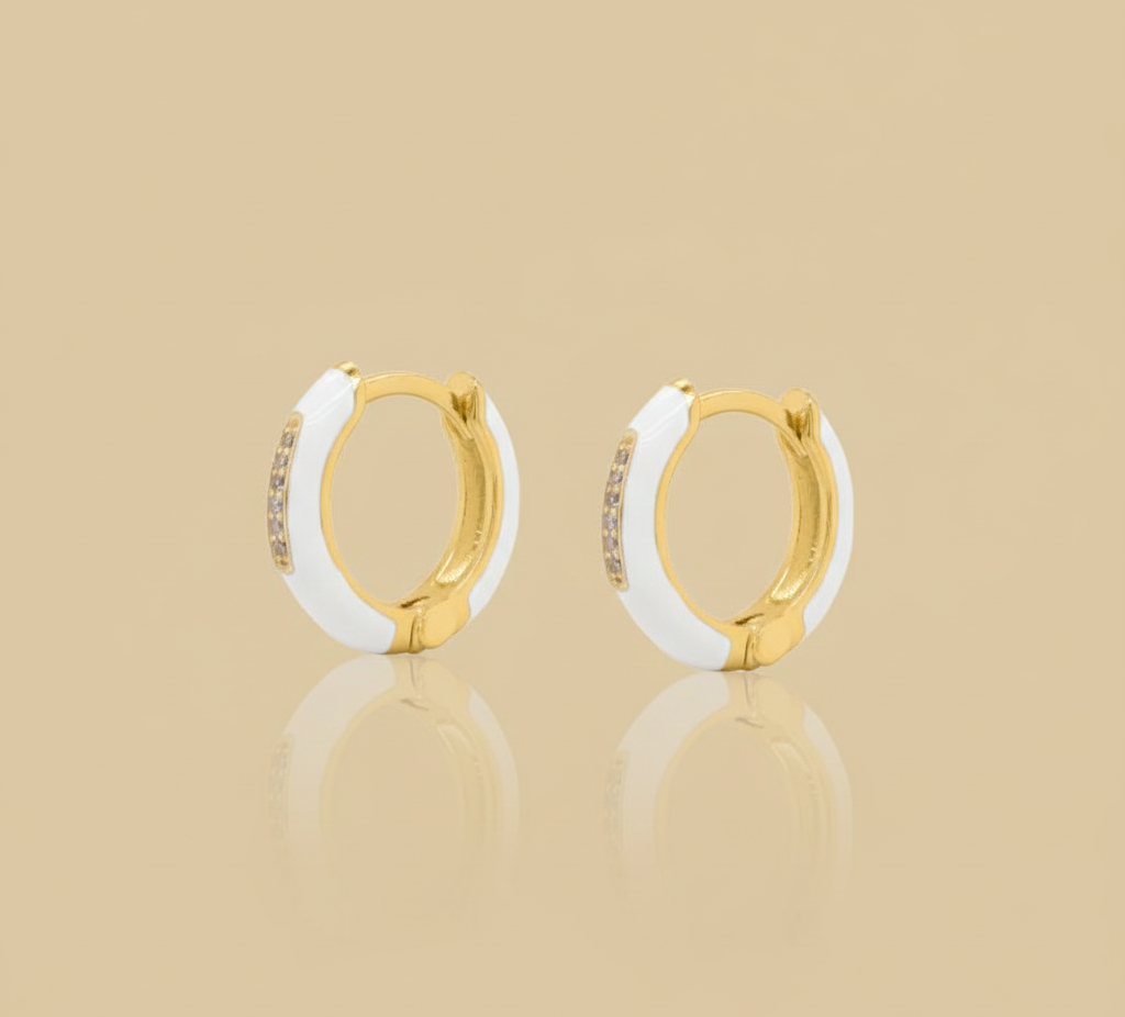 Gold and white hoop earrings on a beige background