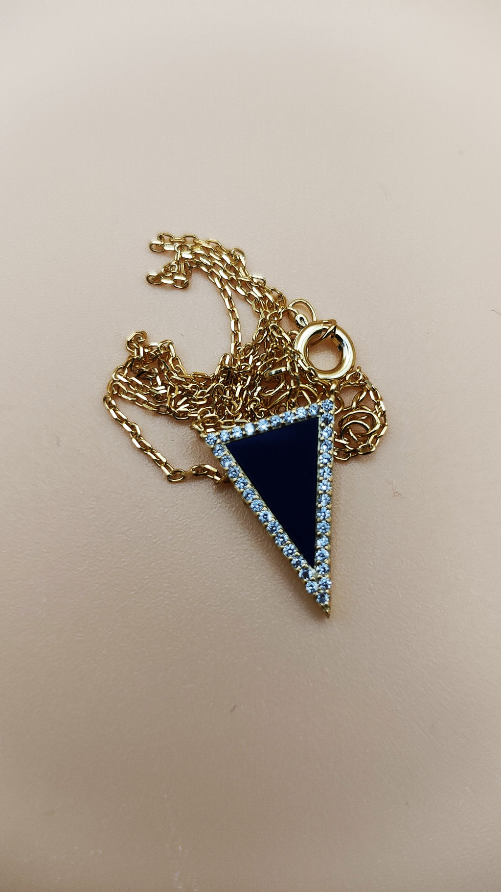 Necklace with a blue triangle pendant on a beige background