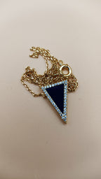 Necklace with a blue triangle pendant on a beige background