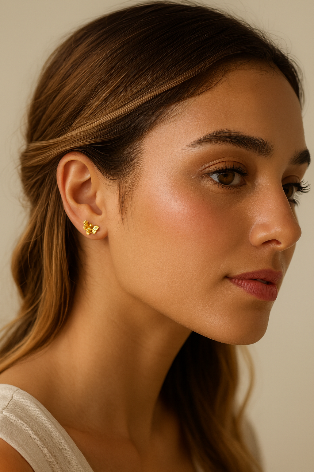 Close-up of a woman wearing a gold earring with a neutral background