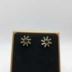 Cose up of  earrings of an anti-tarnish sunflower necklace with a green crystal.