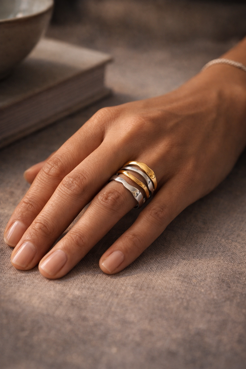 Hand wearing two tone gold and silver ring on a textured surface